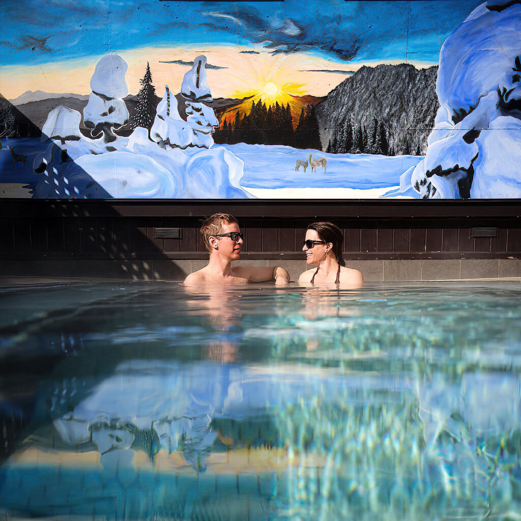 couple sitting in outdoor hot tub of Fernie Fox Hotel