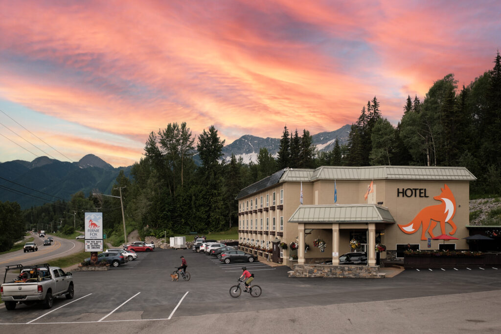 two bikers pedal across parking lot of Fernie Fox Hotel